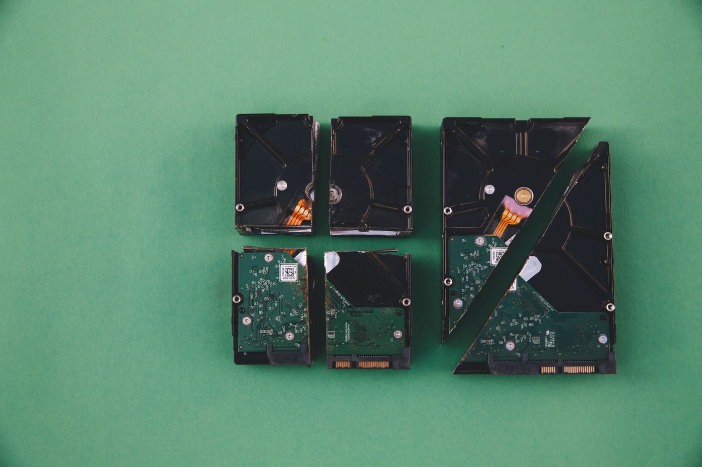 Used computer hard drives arranged on a green surface as an illustration of data disposal