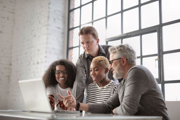 Happy colleagues discussing workplace benefits at a laptop
