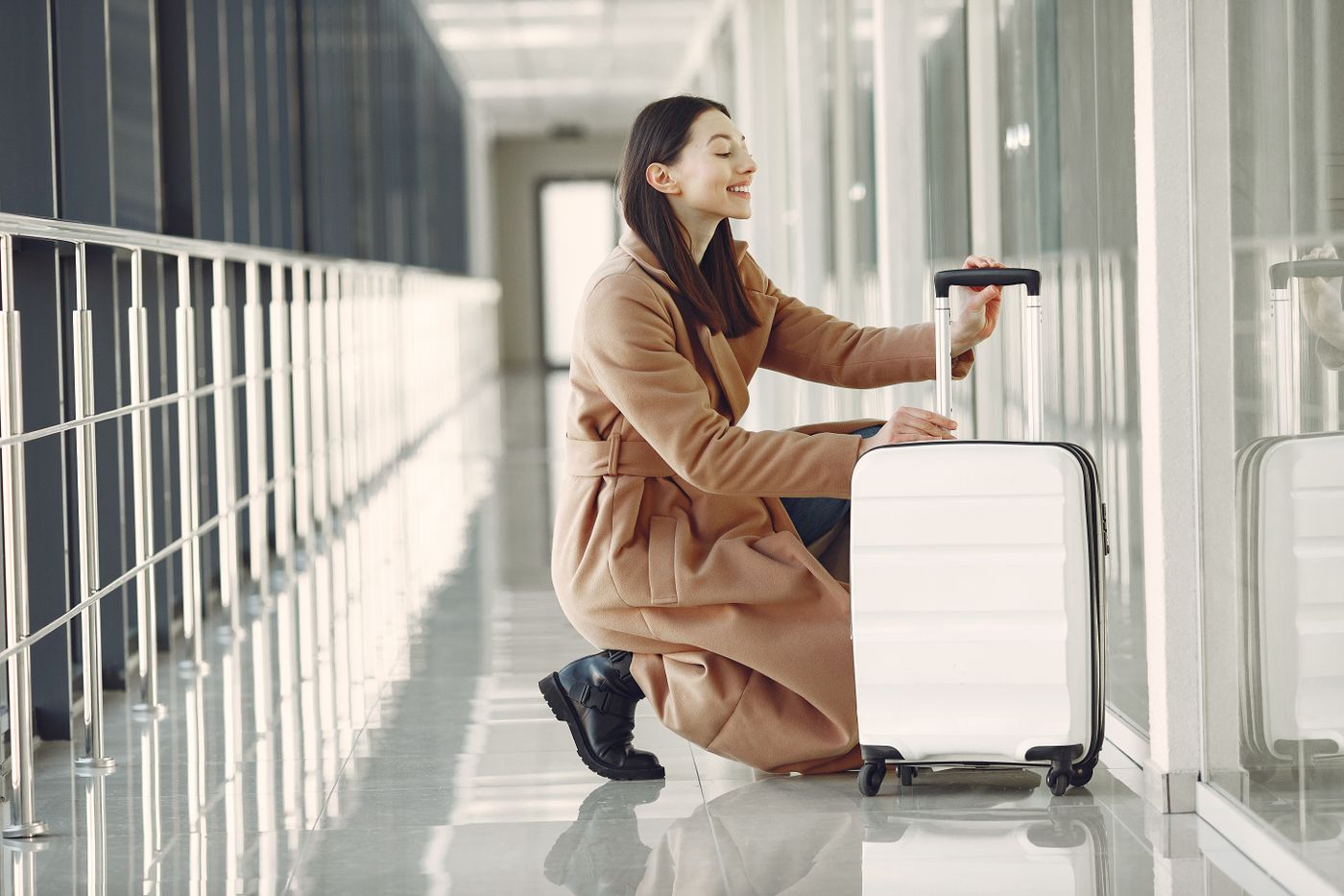 Young woman with luggage waiting in a sunlit airport terminal