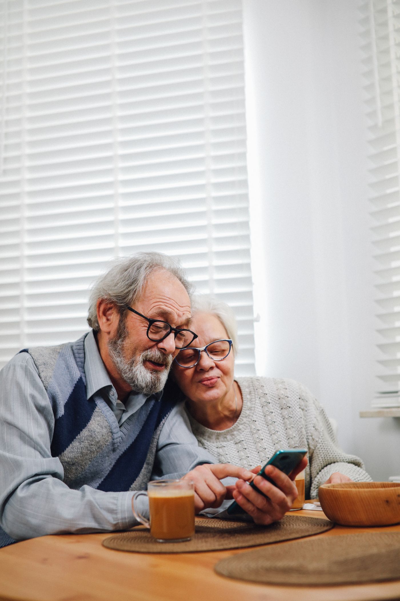 Smiling senior couple using a smartphone together in their home